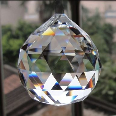 A faceted crystal prism reflecting light with rainbow colours.